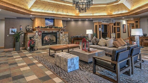 A spacious living room with a fireplace, a seating area with sofas and a coffee table, and a checkered floor.
