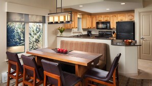 A modern kitchen with wooden cabinets, a central island, and a dining area with a bench and chairs.
