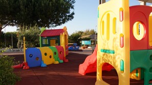 Un espace de jeux pour enfants avec des structures colorées, notamment un toboggan et des éléments d’escalade.