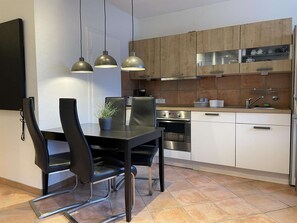 A modern kitchen with a dining area, featuring stainless steel appliances, wooden cabinets, and pendant lighting. - Designer apartment in the immediate vicinity of the bobsleigh run (Winterberg)