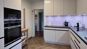 Eine moderne Küche mit weißen Schränken, einem eingebauten Backofen und Holzboden.
