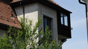 Ein Gebäude mit rotem Ziegeldach, einem Balkon mit schwarzen Geländern und einem Fenster.