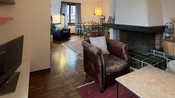 Ein Wohnzimmer mit Kamin, Essbereich und Fernseher.