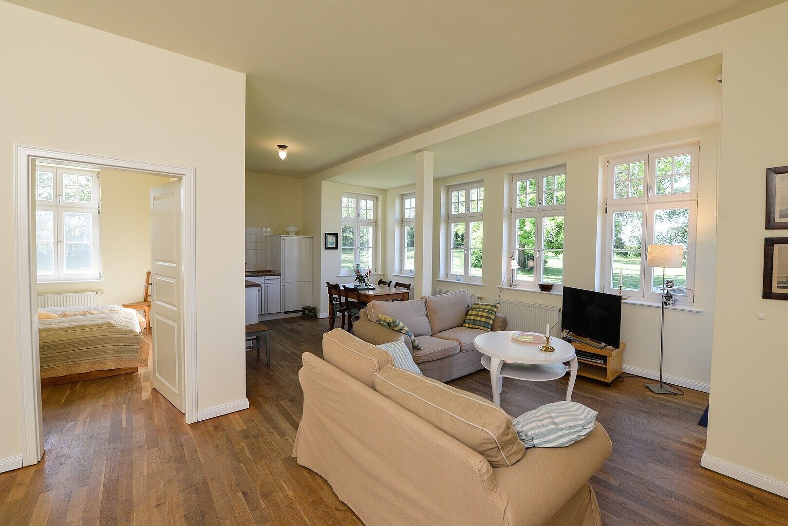 A spacious living area with a sofa, a dining table, and a kitchen in the background.