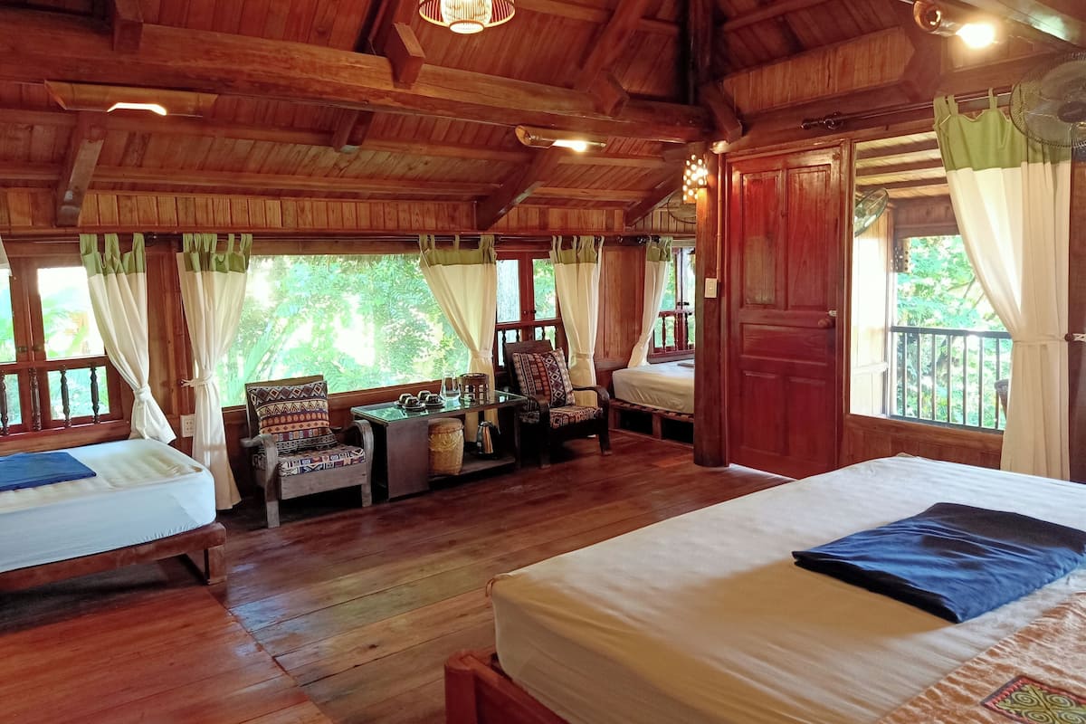Une cabane en bois avec deux lits, une table, des chaises et un ventilateur.