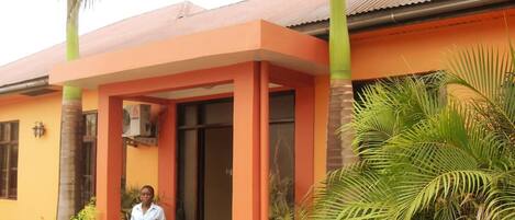 Un bâtiment à la façade d’un orange vif, doté d’un porche et surmonté d’un palmier en premier plan.