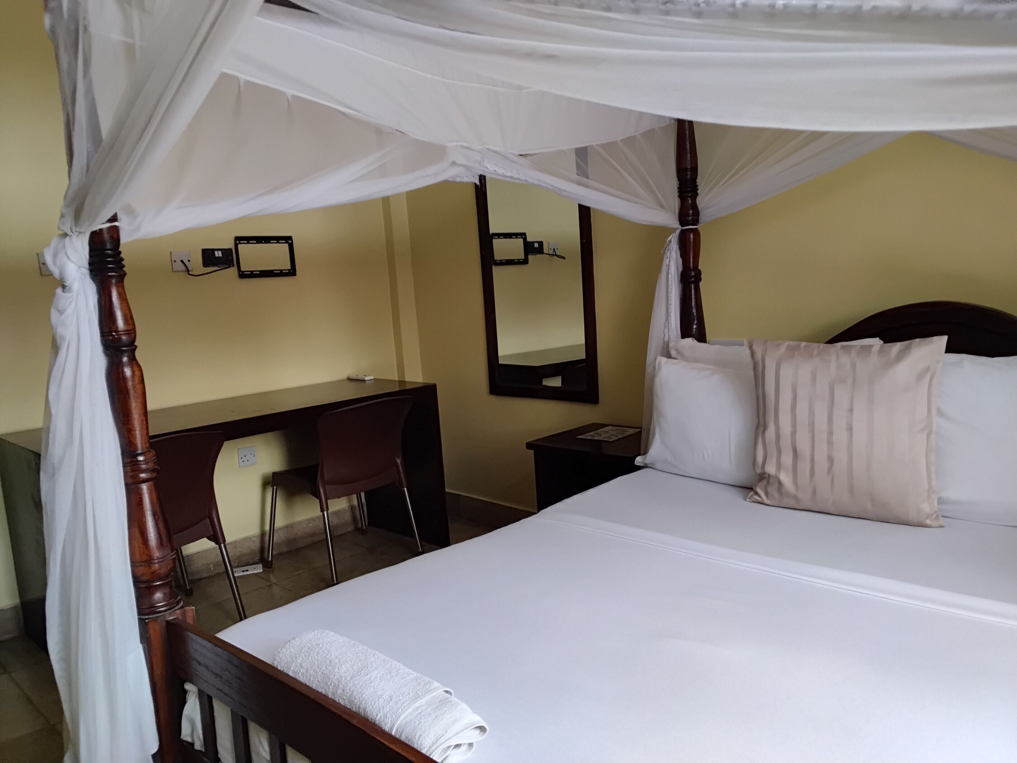 Un dormitorio con cama con dosel, un escritorio y una silla.