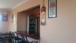 A bar area with a minibar, framed pictures on the wall, and a seating arrangement with chairs.