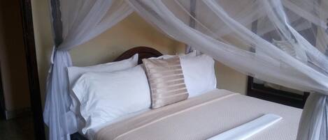 A bed with a canopy, pillows, and a blanket.