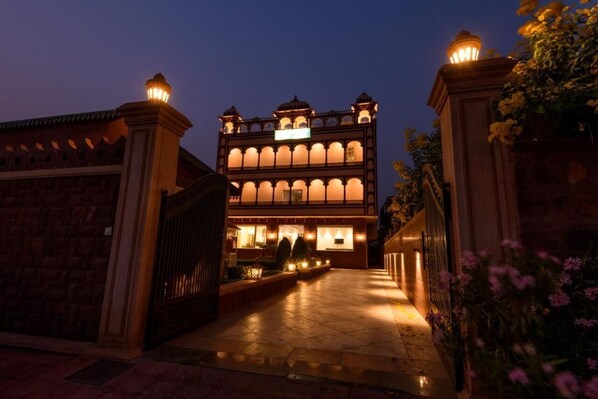 A large, illuminated building with multiple arches and a central entrance, surrounded by well-lit pathways and decorative lighting.
