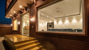 A modern hotel entrance with a wooden facade, a glass door, and a seating area with a blue sofa. - Hotel The Balam (Luni)