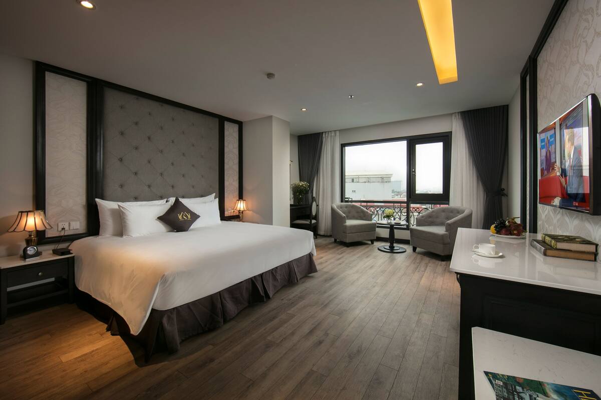 Een hotelkamer met een groot bed, een bureau, een stoel, een raam met uitzicht en een balkon.