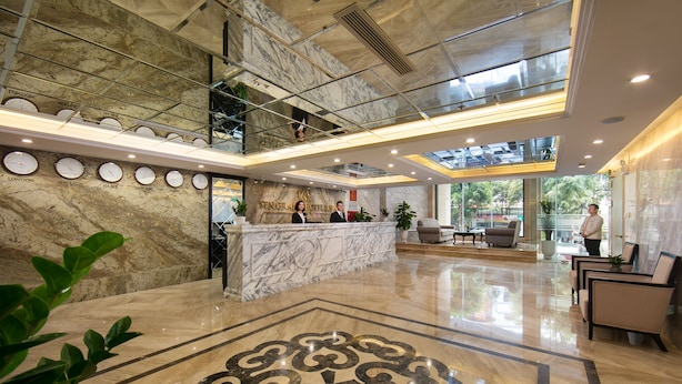 A hotel lobby with a marble reception desk, a large decorative floor pattern, and a glass ceiling. - Sen Grand Hotel & Spa managed by Sen Group (Hanoi)