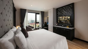 A hotel room with a large bed, a television mounted on the wall, and a view of the city through the window. - Sen Grand Hotel & Spa managed by Sen Group (Hanoi)