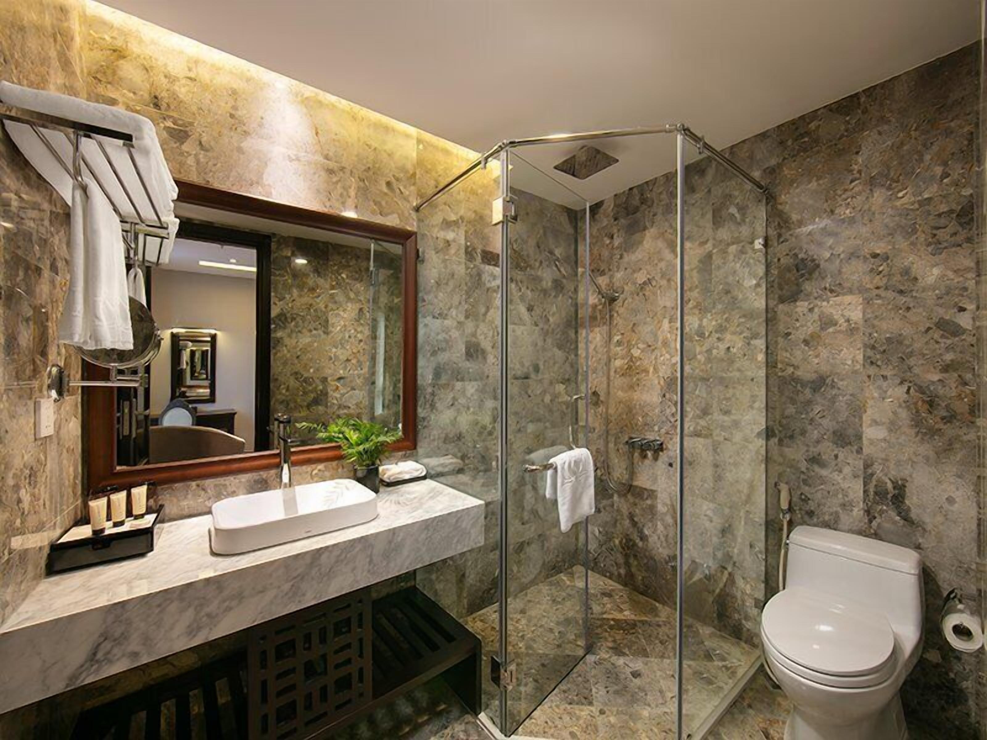 Une salle de bain moderne avec une douche à parois de verre, un lavabo en marbre et des toilettes.