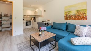 A modern living room with a blue sofa, a coffee table, and a painting on the wall. - Cozy vacation apartment in Heringsdorf just 200 m from the Baltic Sea beach (Seebad Heringsdorf)