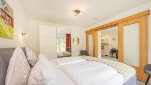 A bedroom with a bed, pillows, a sofa, a desk, and a chair. - Cozy vacation apartment in Heringsdorf just 200 m from the Baltic Sea beach (Seebad Heringsdorf)