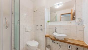 Ein modernes Badezimmer mit Duschkabine aus Glas, Toilette in Weiß, Holzwaschtisch und Spiegel.