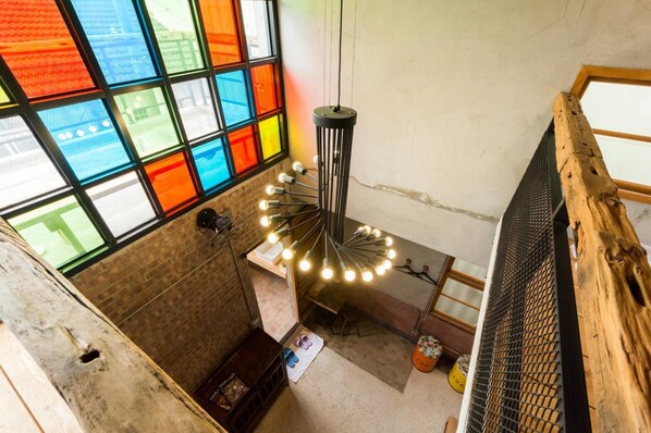 A room with a large window featuring colorful stained glass, a hanging light fixture, and a rustic wooden beam. - Lucky 1960 (Tainan)