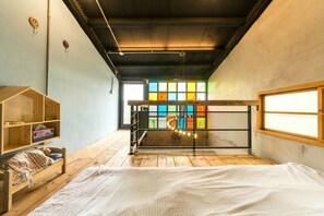 Una habitación acogedora con una cama, un estante de madera y una vista colorida por la ventana.