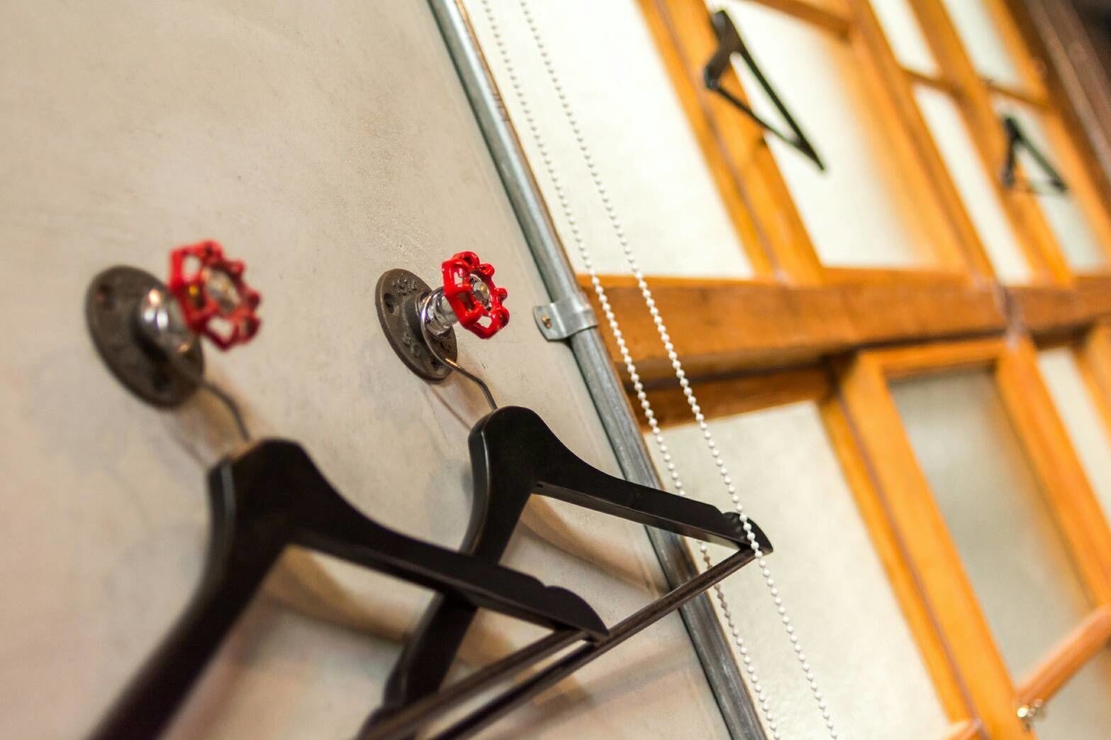 A wall with multiple coat hooks and a mirror.