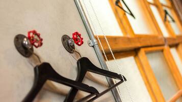 A wall with multiple coat hooks and a mirror.