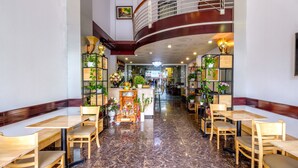 A spacious restaurant with marble flooring, wooden tables and chairs, and a curved ceiling. - Coop's Hotel & Apartments (Da Nang)