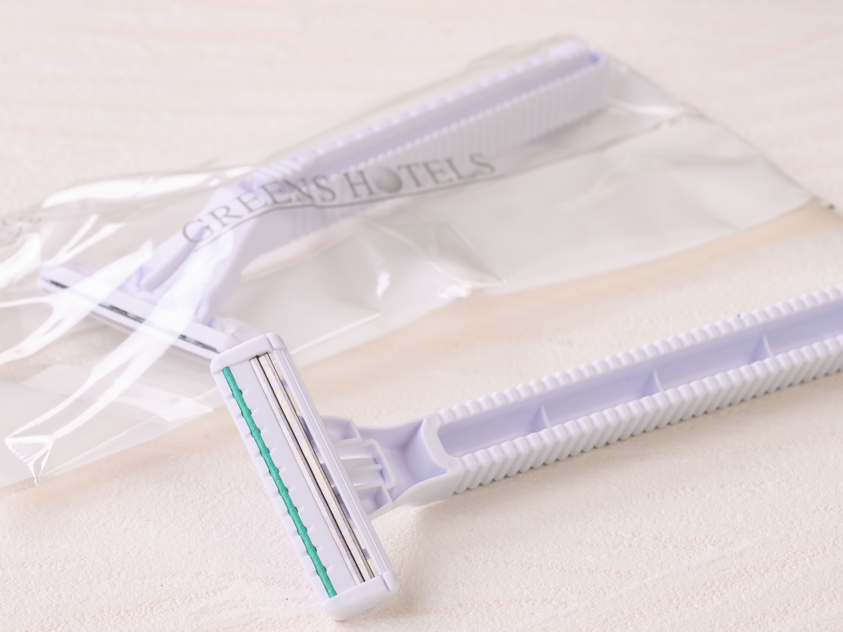 Un rasoir et une lame de rasoir dans un sac en plastique transparent, sur lequel figure le texte « GREEN'S HOTELS ».