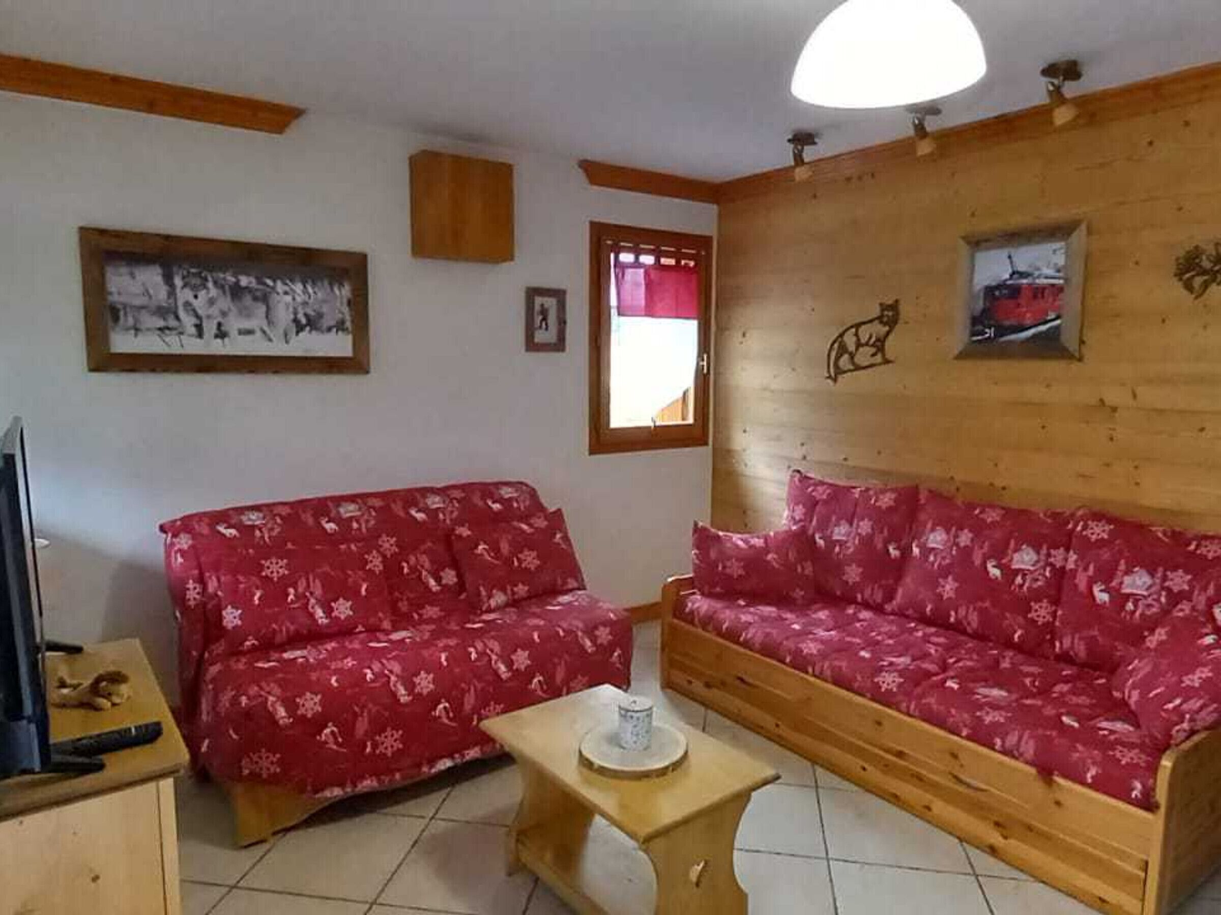 Una sala de estar acogedora con un sofá de madera, una mesita pequeña de madera y un colgador de techo.