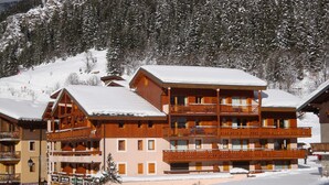 A multi-story hotel with balconies and a ski slope in the background. - Beautiful apartment in Pralognan center with parking (Pralognan-la-Vanoise)