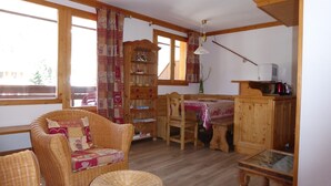 A cozy room with wicker furniture, a wooden table, and a bookshelf. - Beautiful apartment in Pralognan center with parking (Pralognan-la-Vanoise)