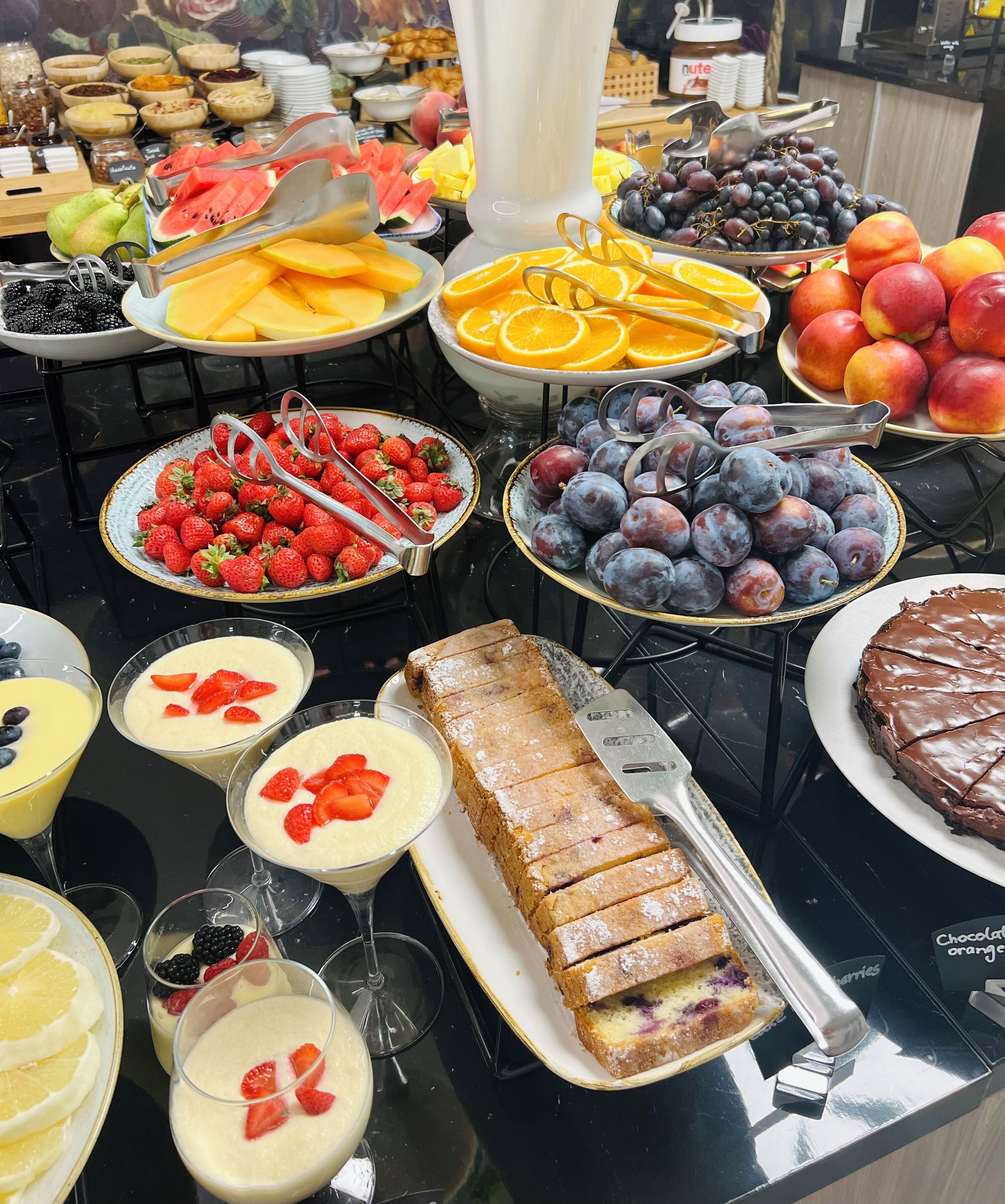 Een buffet met diverse soorten fruit, desserts en drankjes.