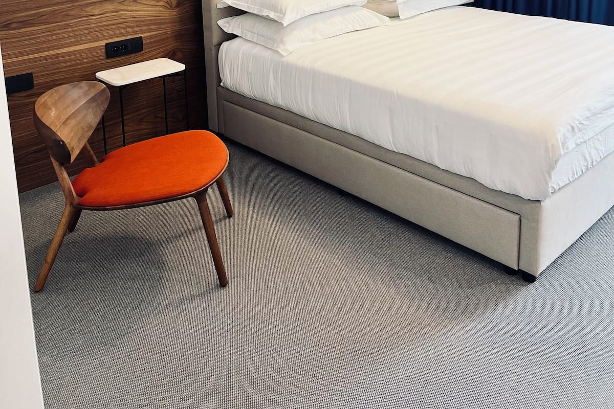 A hotel room with a bed, a desk, a chair, and a blue curtain.