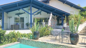 Área externa coberta com piscina, paredes de pedra e diversas plantas.