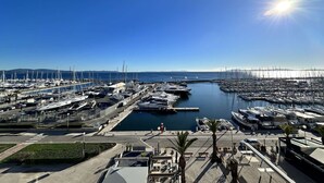 Un puerto deportivo con barcos amarrados, cielo despejado y sol brillante.
