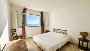 Un dormitorio con una cama, un escritorio de madera, una silla, una ventana con cortinas y una lámpara.