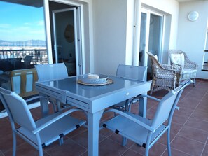 A balcony with a table and chairs, a view of the sea, and a door leading to an outdoor area. - FRONT DE MER, beautiful apartment with all comforts (L'Escala)