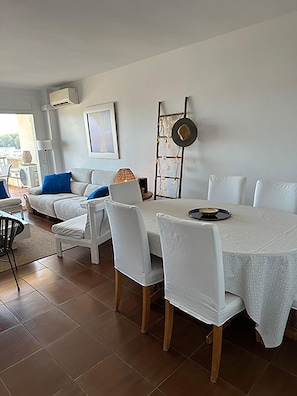 A dining area with a table set for four, white chairs, a white tablecloth, and a decorative ladder with hanging lights.