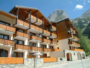 Um hotel com vários andares, varandas de madeira e paredes de pedra.