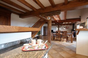 A kitchen with granite countertops, a wooden staircase, and a dining area with chairs and a table.
