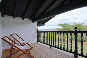 A balcony with wooden flooring and a black balustrade.