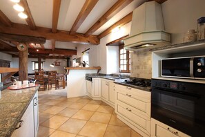 A kitchen with a central island, wooden beams, a microwave, oven, and a sink. - BEAUTIFUL HOUSE WITH MAGNIFICENT VIEW (Sare)