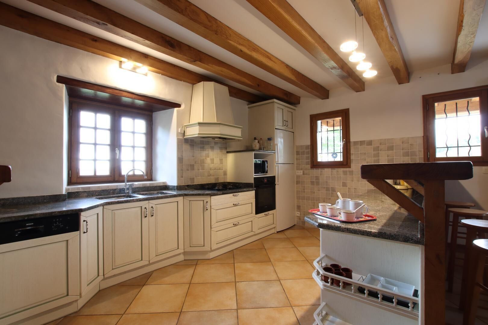 Een keuken met witte kastjes, een zwart aanrecht, een ingebouwde oven en een raam met uitzicht.