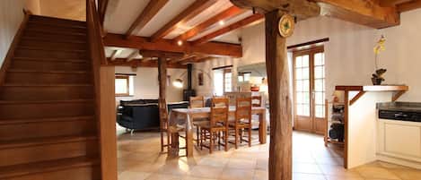 A spacious kitchen with wooden beams, a dining area with a table and chairs, and a staircase leading to another level.
