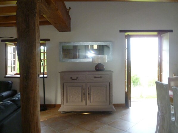 A room with a wooden ceiling, a white cabinet with drawers, a mirror above it, and a window with blinds.
