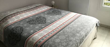 Un dormitorio con cama, mesita de noche, lámpara de pared y radiador.