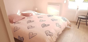 A bedroom with a bed, a chair, and a window.