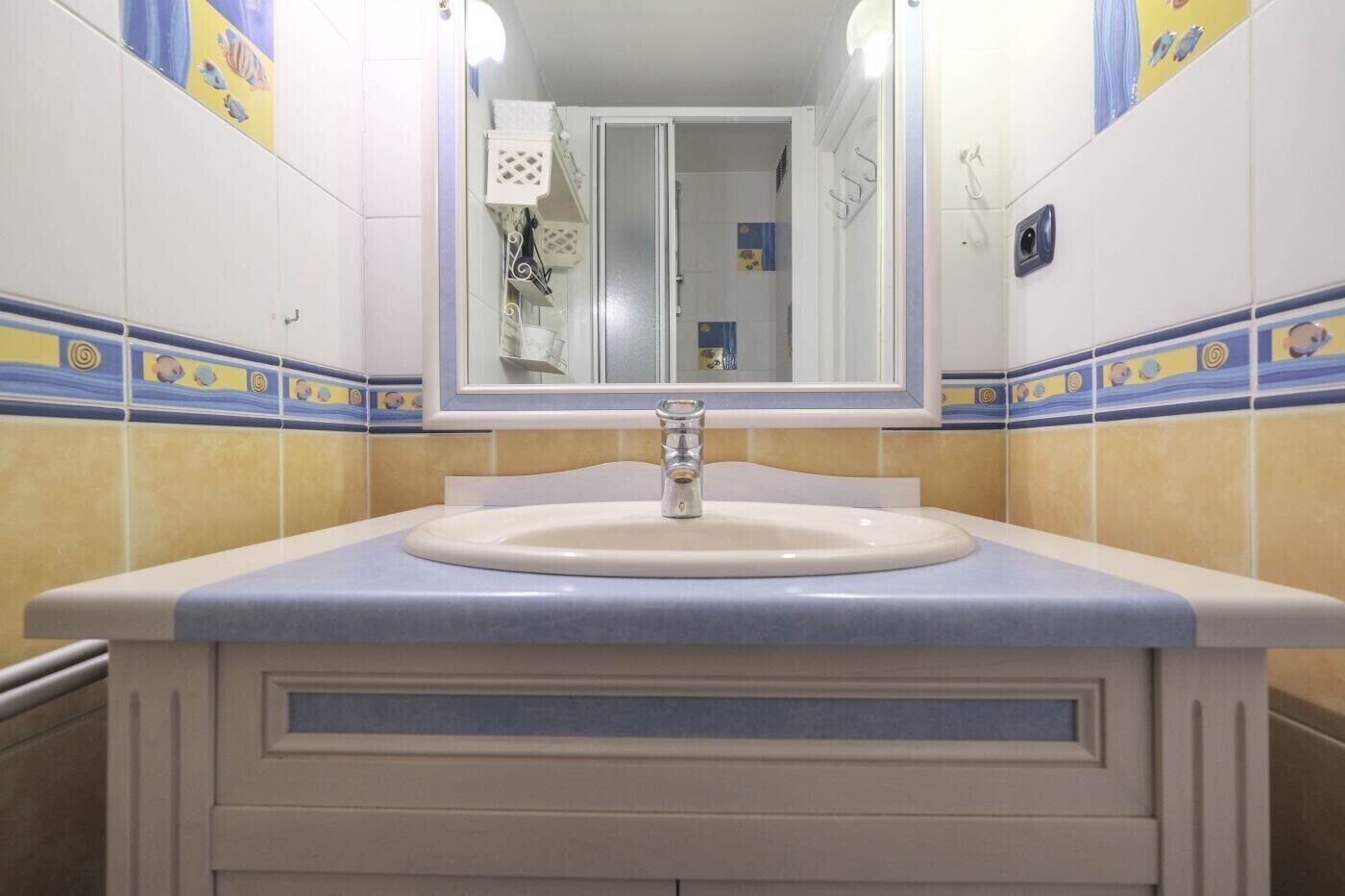 A bathroom with a sink, mirror, and tiled walls.