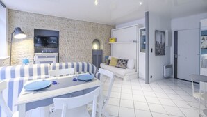 Una sala moderna con comedor, sofá, televisor y área de cocina.