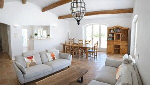 Ein Wohnzimmer mit einer Couch, einem Holztisch und einem Essbereich mit Tisch und Stühlen.